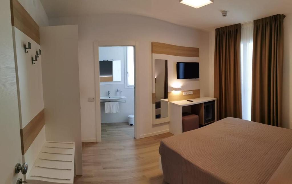 une chambre d'hôtel avec un lit et un bureau avec une télévision dans l'établissement Almalux Jesolo Wellness & Spa 3 stelle superior, à Lido di Jesolo