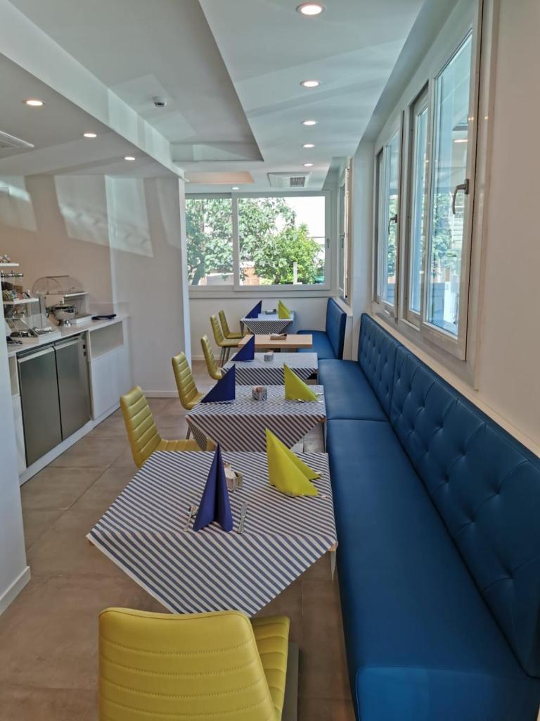 une salle à manger avec quatre tables et des chaises jaunes dans l'établissement Almalux Jesolo Wellness & Spa 3 stelle superior, à Lido di Jesolo