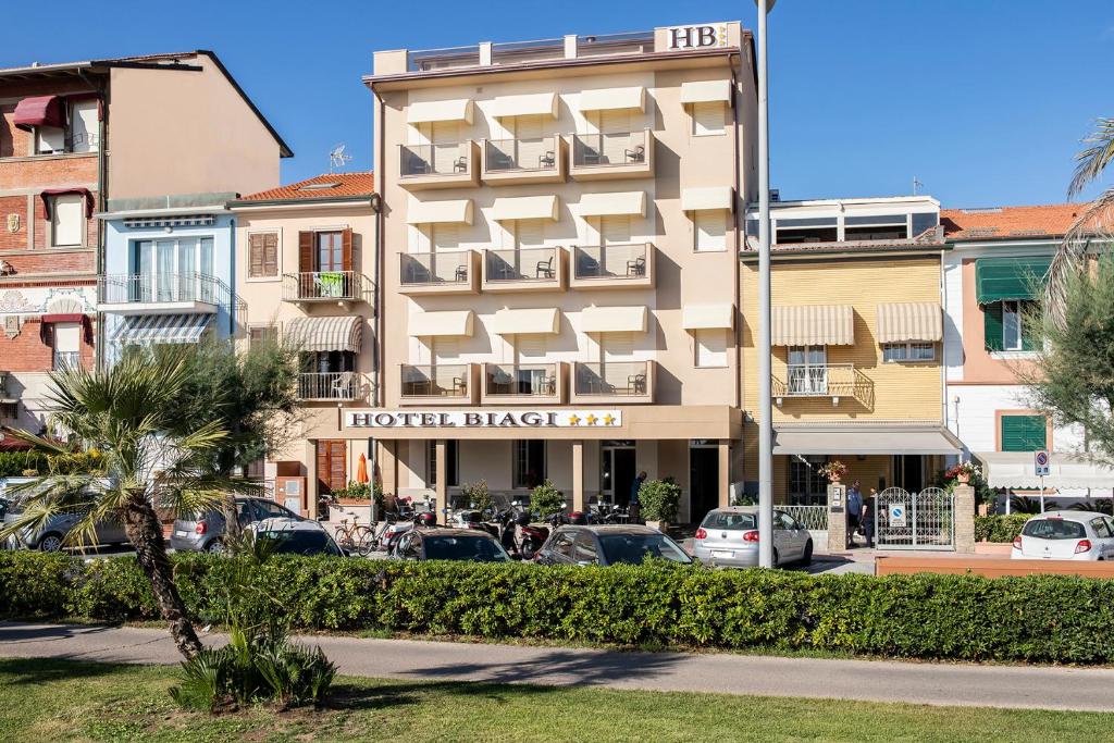 un pâté de maisons d'hôtel avec des voitures garées dans un parking dans l'établissement Hotel Biagi & Residence, à Lido di Camaiore