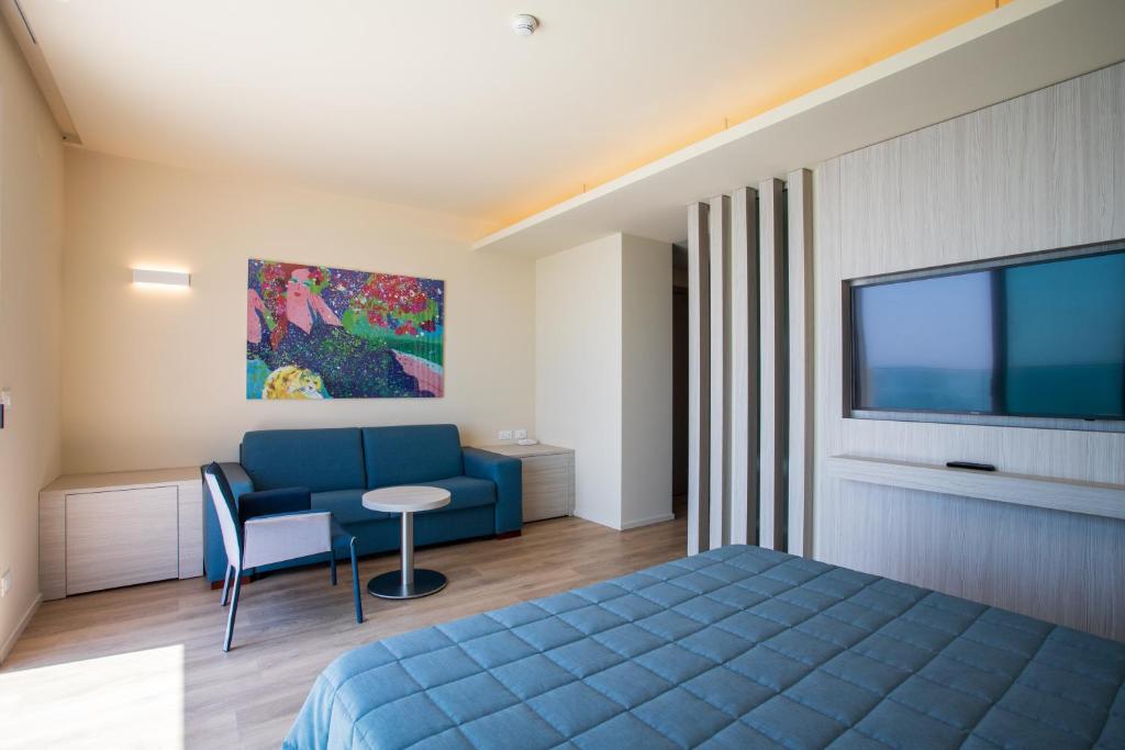- une chambre avec un lit bleu et une télévision dans l'établissement Hotel Ancora, à Lido di Jesolo
