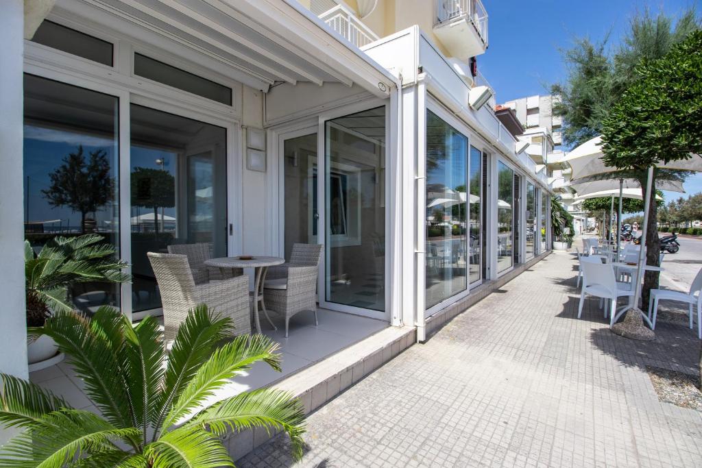 un patio avec des chaises et des tables sur un bâtiment dans l'établissement Hotel B&B Sole, à Senigallia