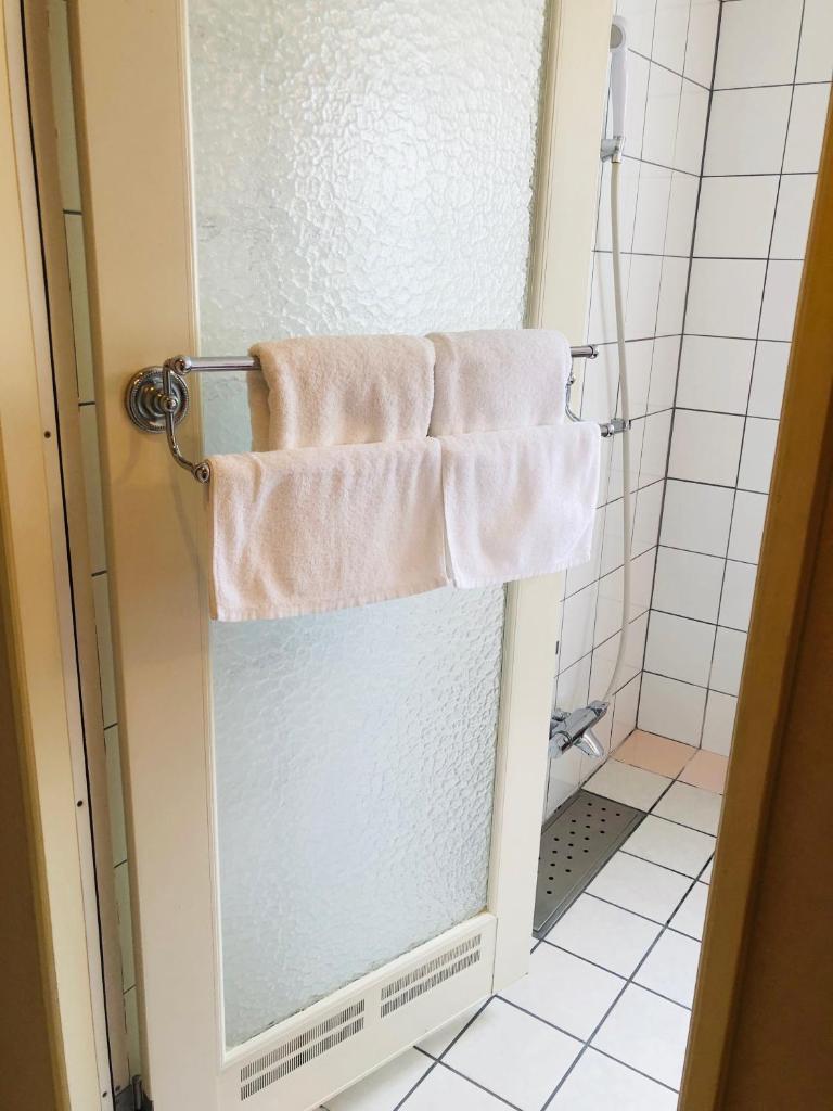 La salle de bains est pourvue d'une serviette suspendue à une porte de douche. dans l'établissement Hotel Star Dust (Adult Only), à Hiroshima