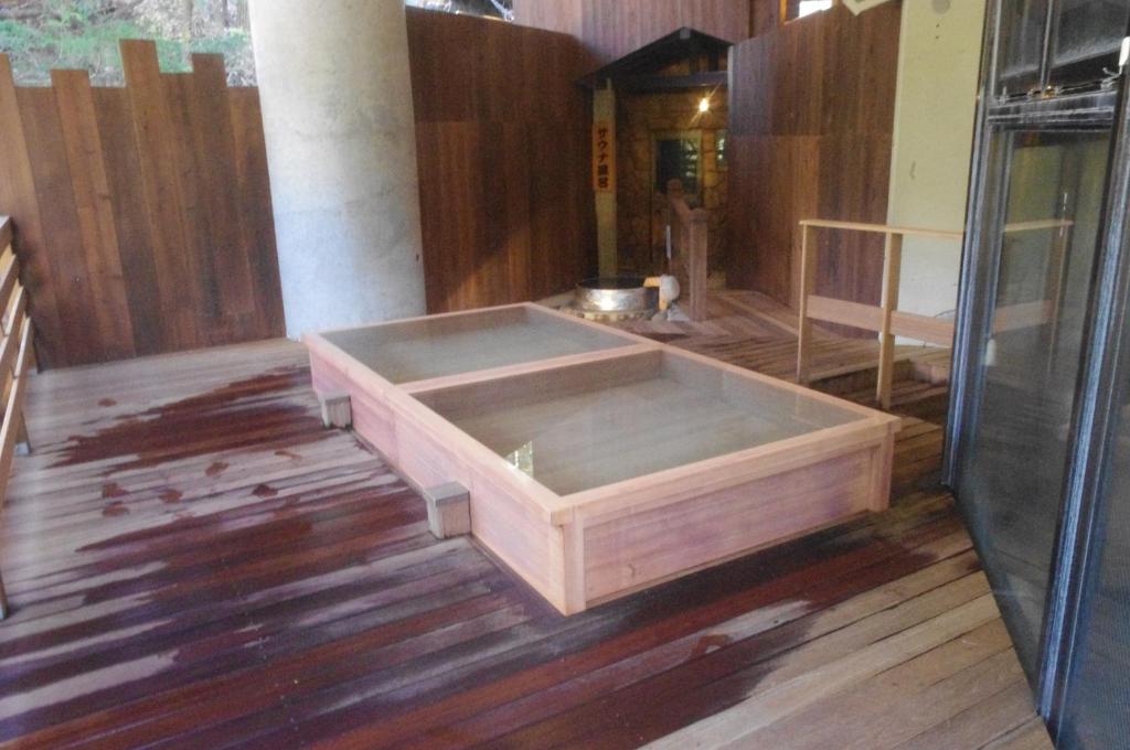 - une grande baignoire en bois assise sur du parquet dans l'établissement Hotel Manyotei, à Nikkō