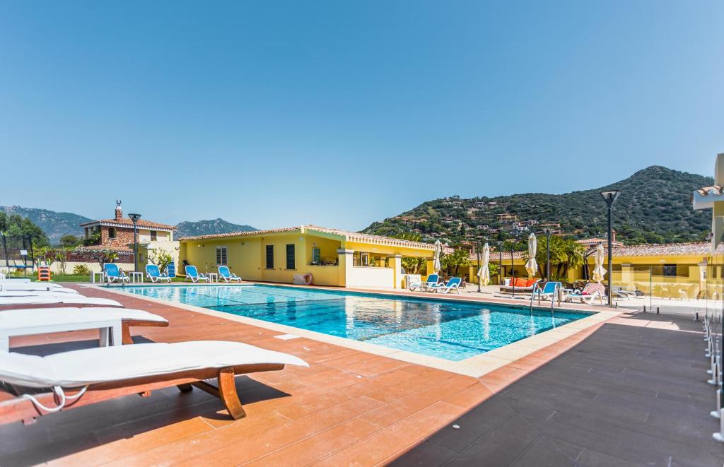 - une piscine avec des chaises et un complexe dans l'établissement Hotel Fiore Di Maggio, à Villasimius