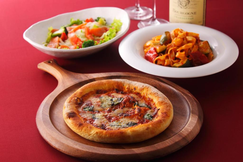 une table avec une pizza et une assiette de nourriture dans l'établissement Hotel Y's (Adult Only), à Sapporo