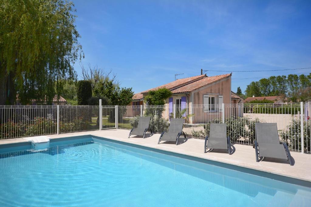 une piscine avec trois chaises longues et une maison dans l'établissement Mas et Gite de la Picholine, à LʼIsle-sur-la-Sorgue