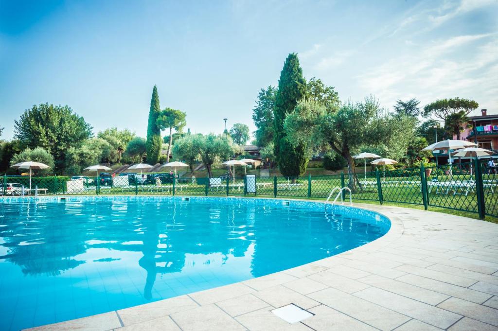 une piscine avec une clôture et des parasols dans l'établissement Club del Sole Desenzano Boutique Resort, à Desenzano del Garda