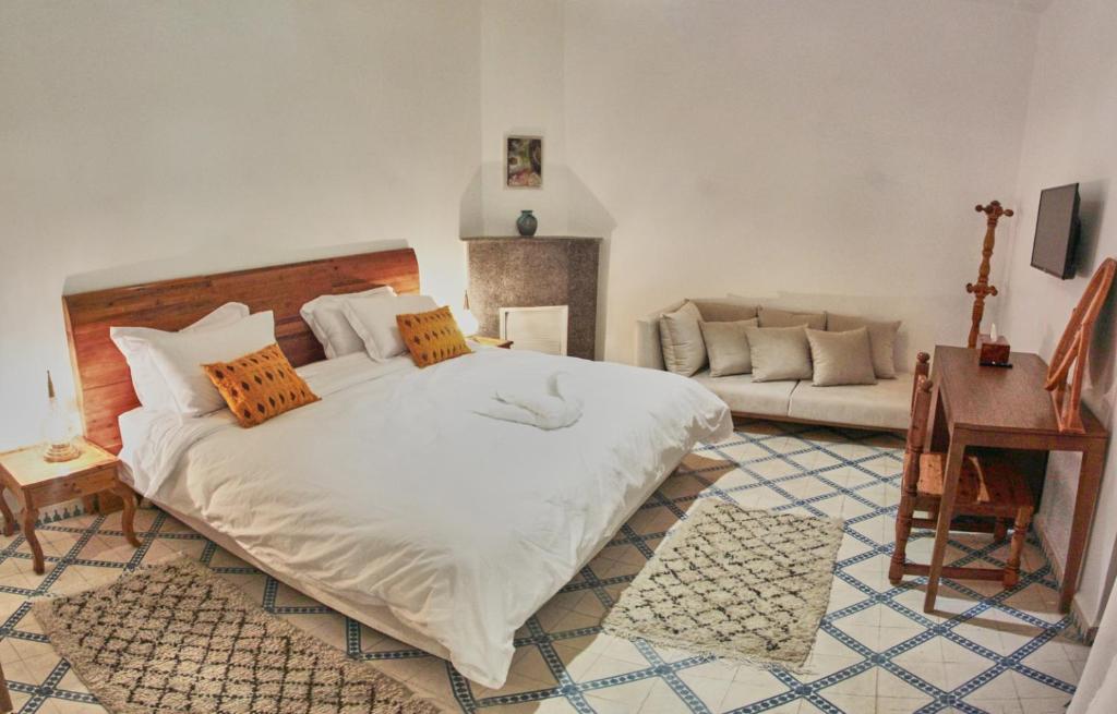 une chambre avec un grand lit blanc et un canapé dans l'établissement Riad Borj El Baroud, à Essaouira