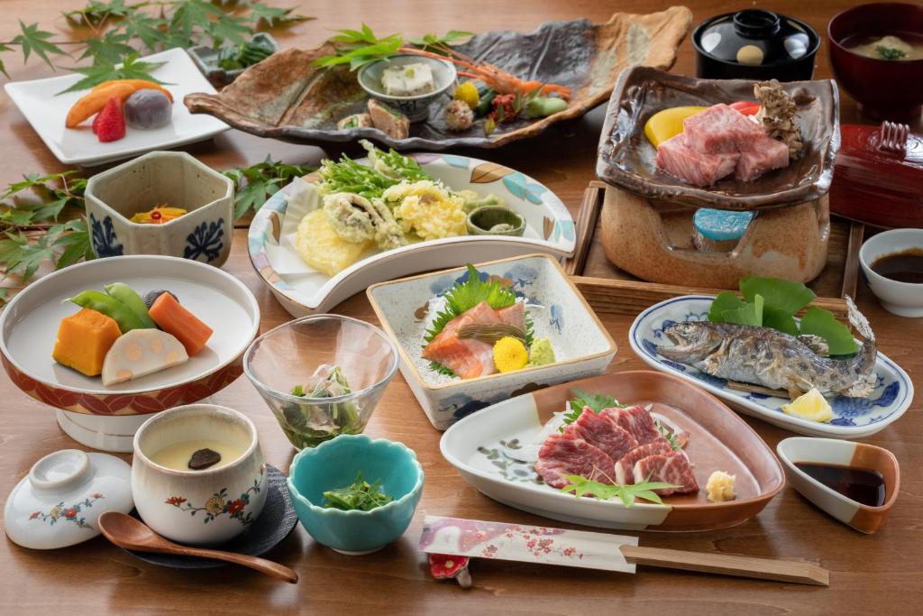 une table avec de nombreuses assiettes de nourriture dessus dans l'établissement Ryokan Nanjoen, à Minamioguni 36 autres photos