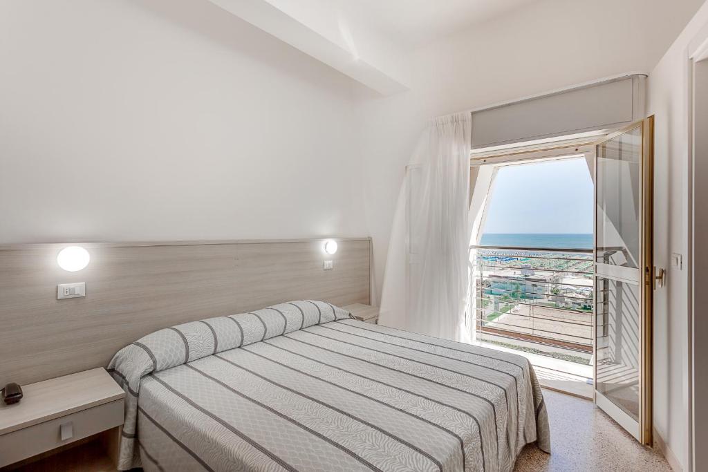 une chambre avec un lit et une grande fenêtre dans l'établissement Hotel Blues, à Cervia