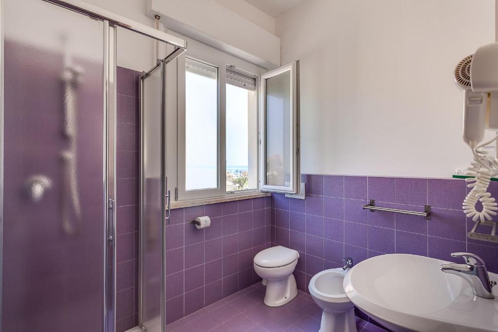 une salle de bains pourpre avec toilettes et lavabo. dans l'établissement Hotel Blues, à Cervia 39 autres photos
