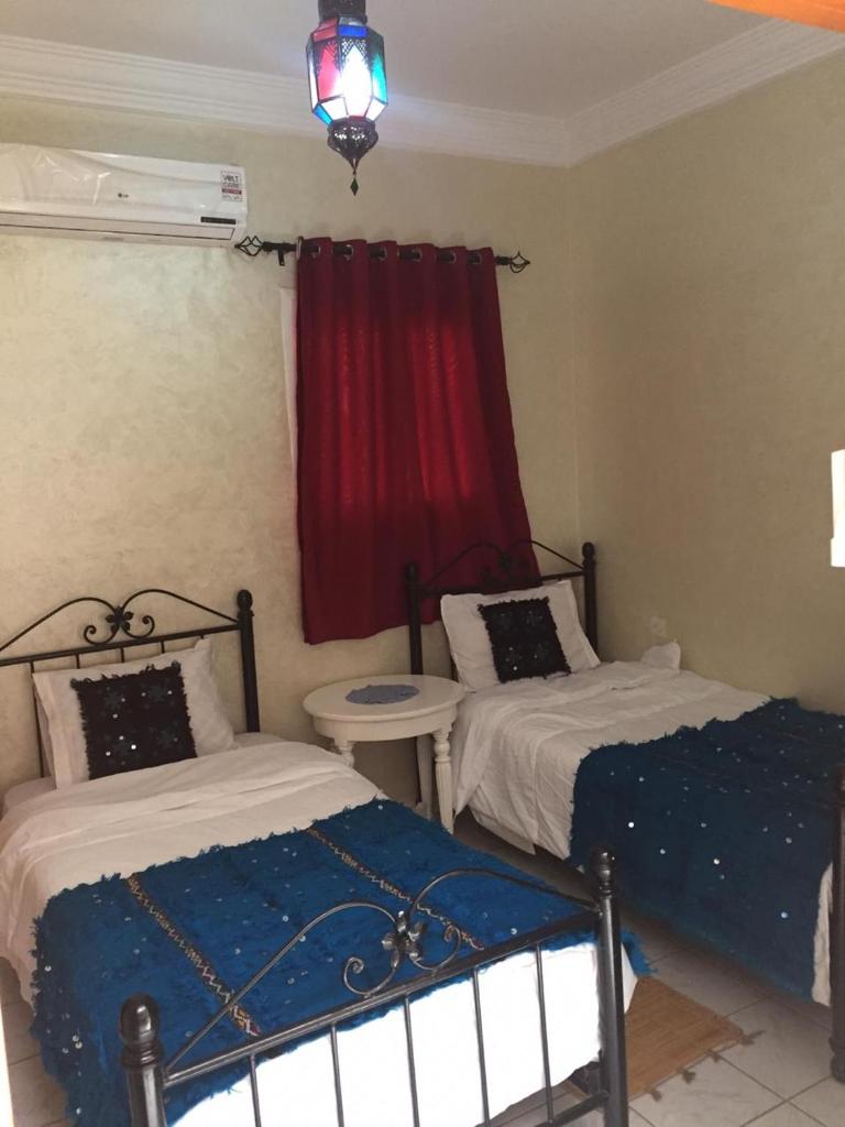 - une chambre avec 2 lits et un rideau rouge dans l'établissement Riad Lalla Zahra, à Marrakech