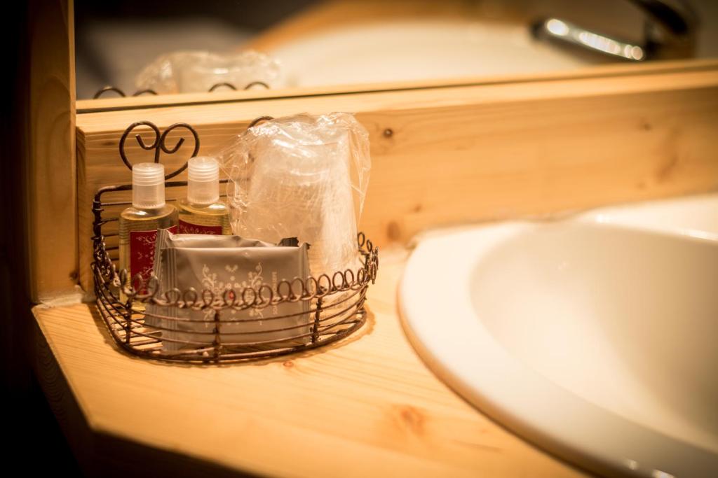 - un lavabo dans la salle de bains avec un panier à côté d'un lavabo dans l'établissement Montana Chalet Hôtel & Spa, au Sauze