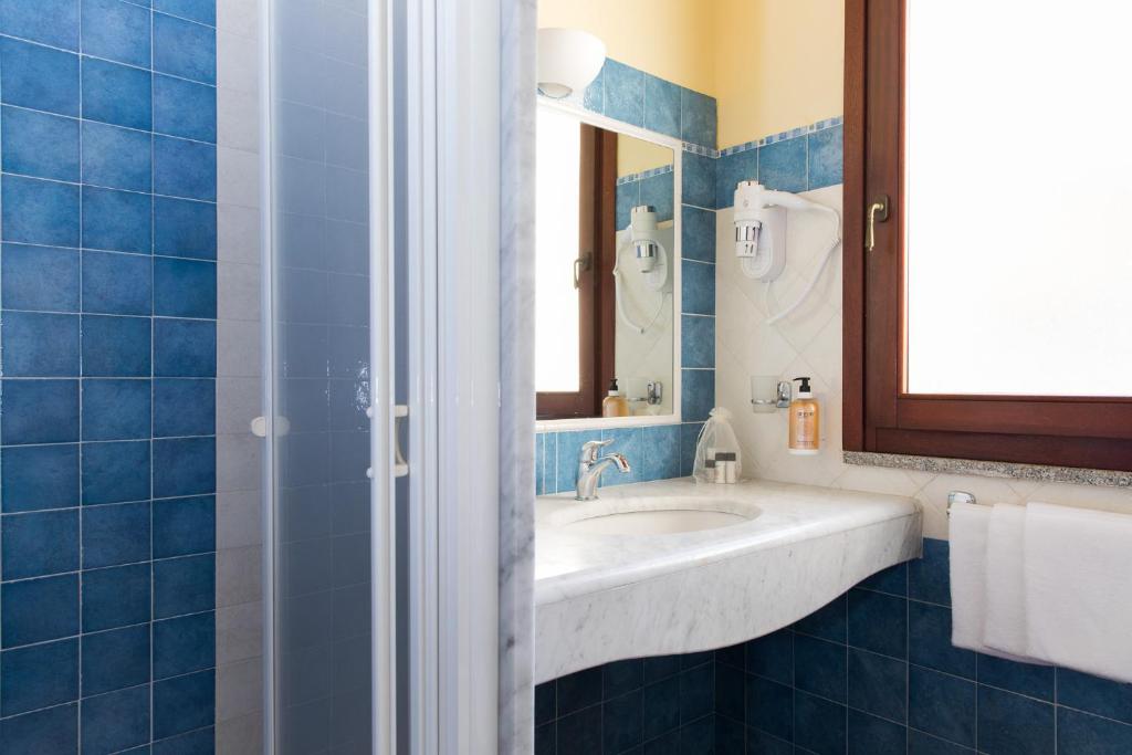 une salle de bain avec un lavabo et un miroir dans l'établissement Cala Luas Resort, à Cardedu