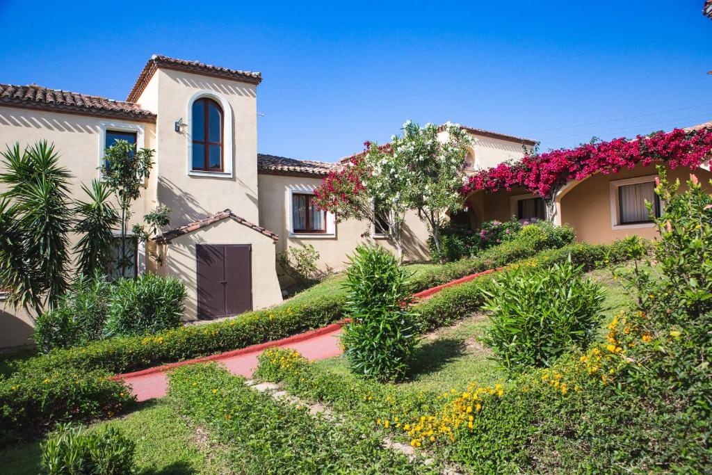 une maison avec un jardin agrémenté de fleurs et de plantes dans l'établissement Cala Luas Resort, à Cardedu