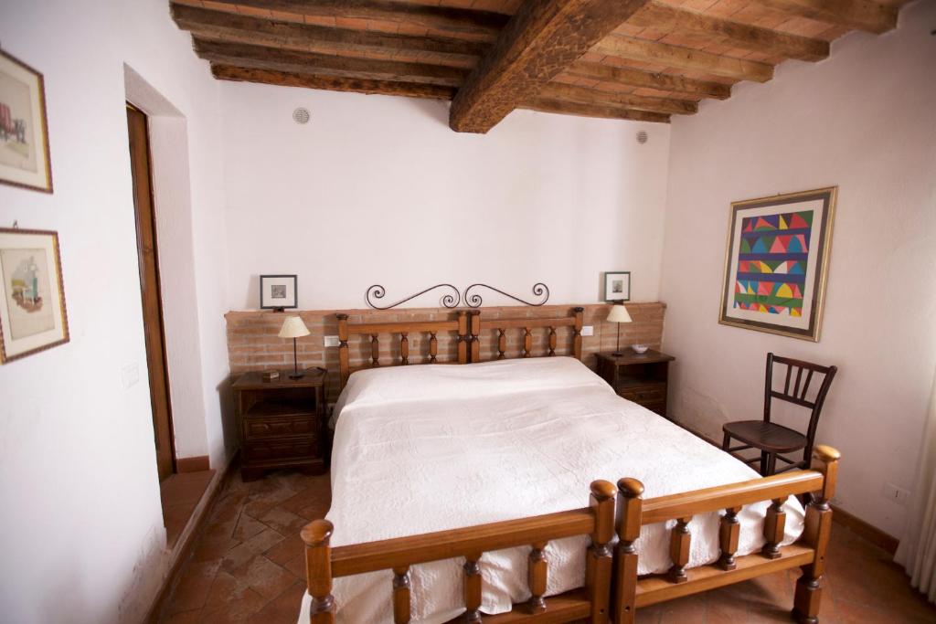 une chambre avec un lit en bois et une chaise dans l'établissement Casale Le Borghe - Montalcino,Toscana, à San Giovanni dʼAsso