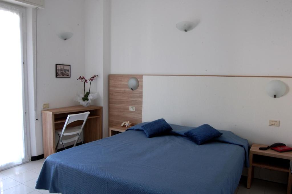 - une chambre avec un lit bleu et un bureau dans l'établissement Residence Sangiorgi, à Cattolica