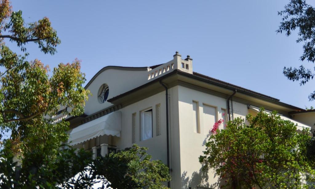 une maison blanche avec des arbres devant dans l'établissement Hotel Club i Pini - Residenza d'Epoca in Versilia, à Lido di Camaiore