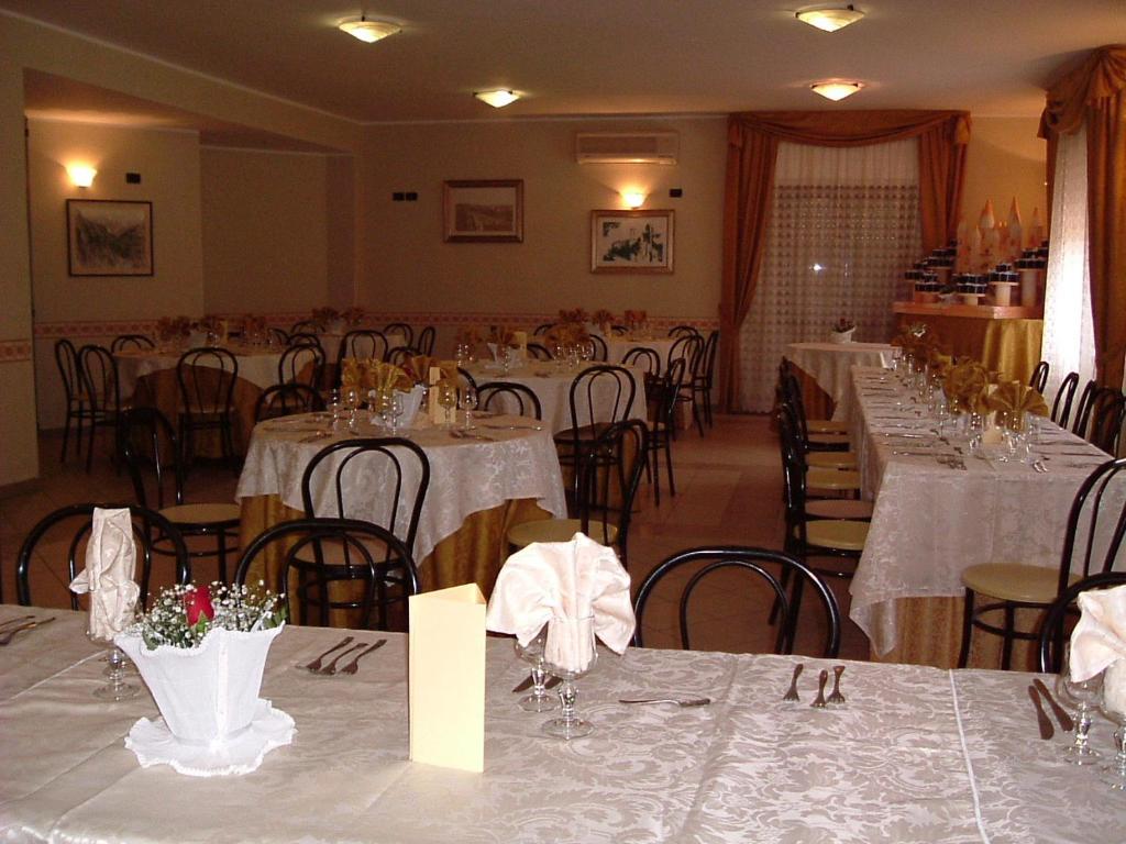 une salle à manger avec tables et chaises avec du linge de table blanc dans l'établissement Hotel Costa Jonica, à Sellia Marina