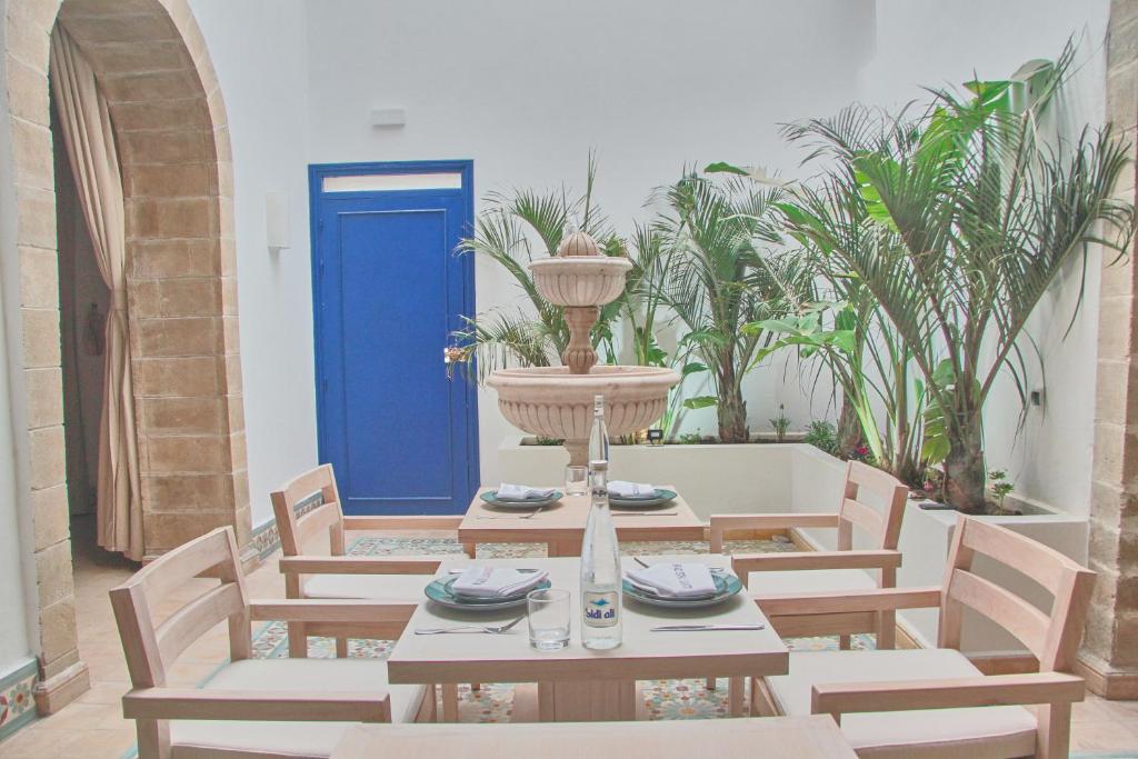 une table et des chaises avec une porte bleue et des plantes dans l'établissement Riad Borj El Baroud, à Essaouira