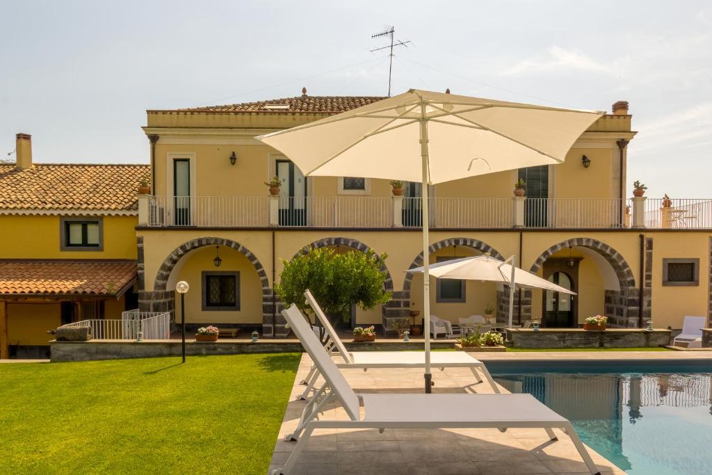 - une piscine avec une chaise et un parasol à côté d'une maison dans l'établissement Dimora Cariga - Home & pool, à Giarre 14 autres photos