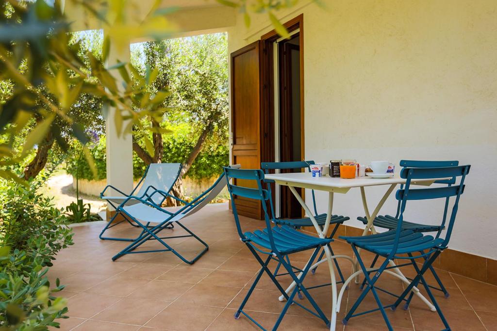 une table et des chaises assises sur une terrasse dans l'établissement Casale la Macina Residence Scopello, à Scopello