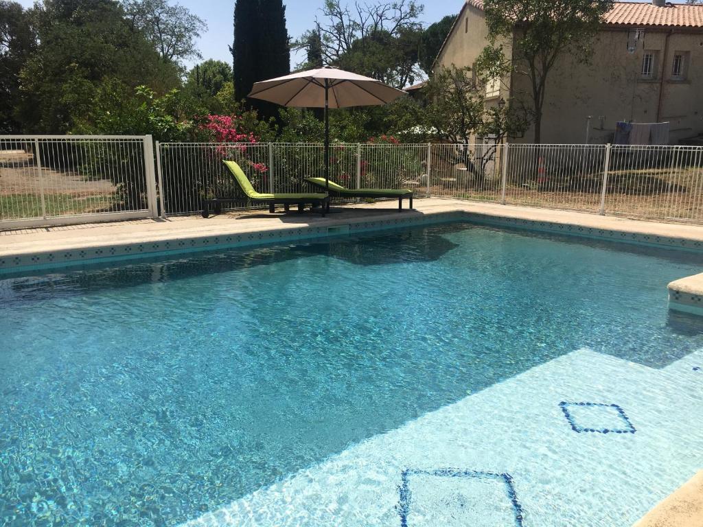 - une piscine avec une chaise et un parasol dans l'établissement Les Gites De La Serre, à Saint-Thibéry
