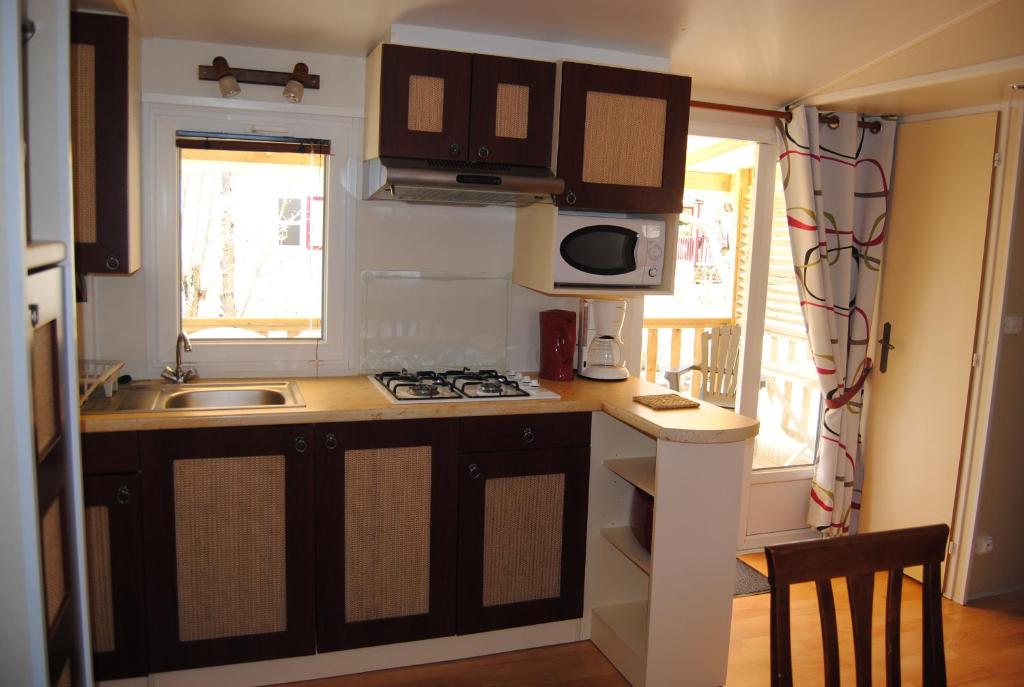 une petite cuisine avec un évier et une cuisinière dans l'établissement MOBILHOME 3 CHAMBRES, à Veyrignac 2 autres photos