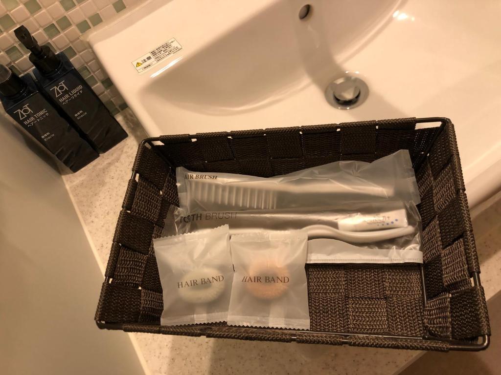 - un panier avec des brosses à dents et du dentifrice sur un lavabo dans l'établissement New Welcity Yugawara, à Atami
