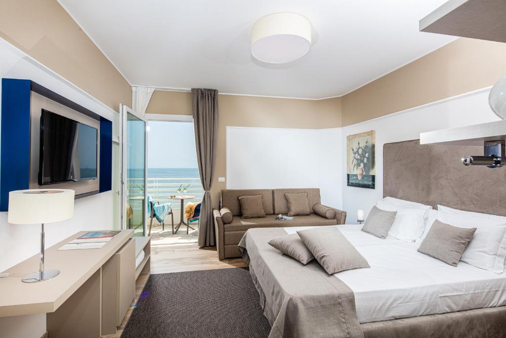 une chambre avec un lit, une télévision et un canapé dans l'établissement Hotel Capitol, à Lido di Jesolo