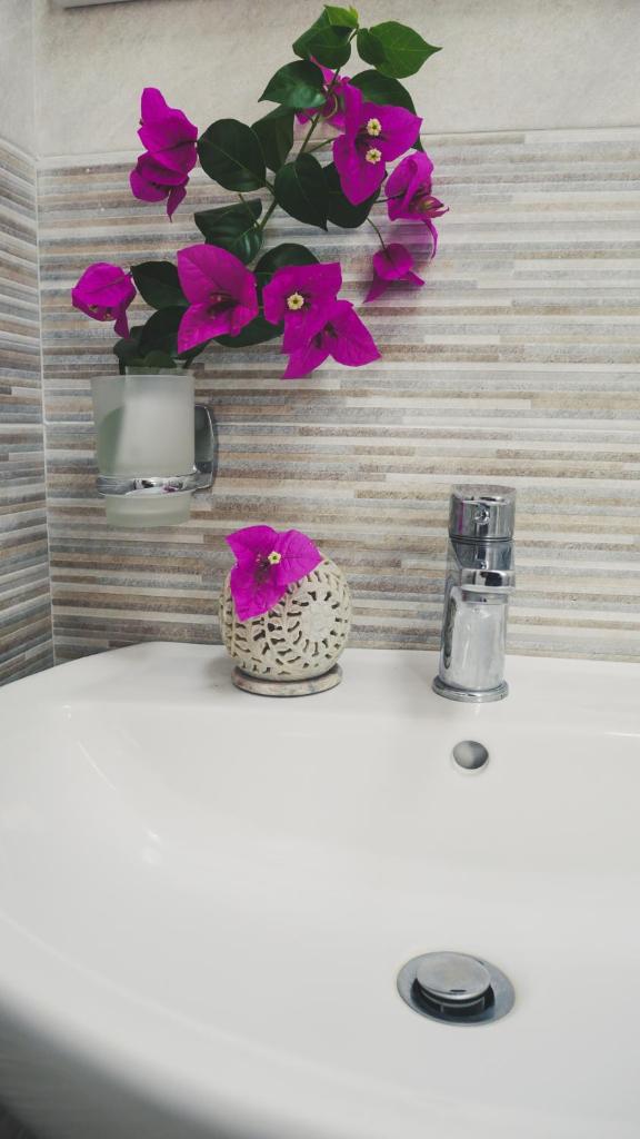 un lavabo de salle de bain avec un vase avec des fleurs roses dessus dans l'établissement Le 7 sorelle, à Lipari