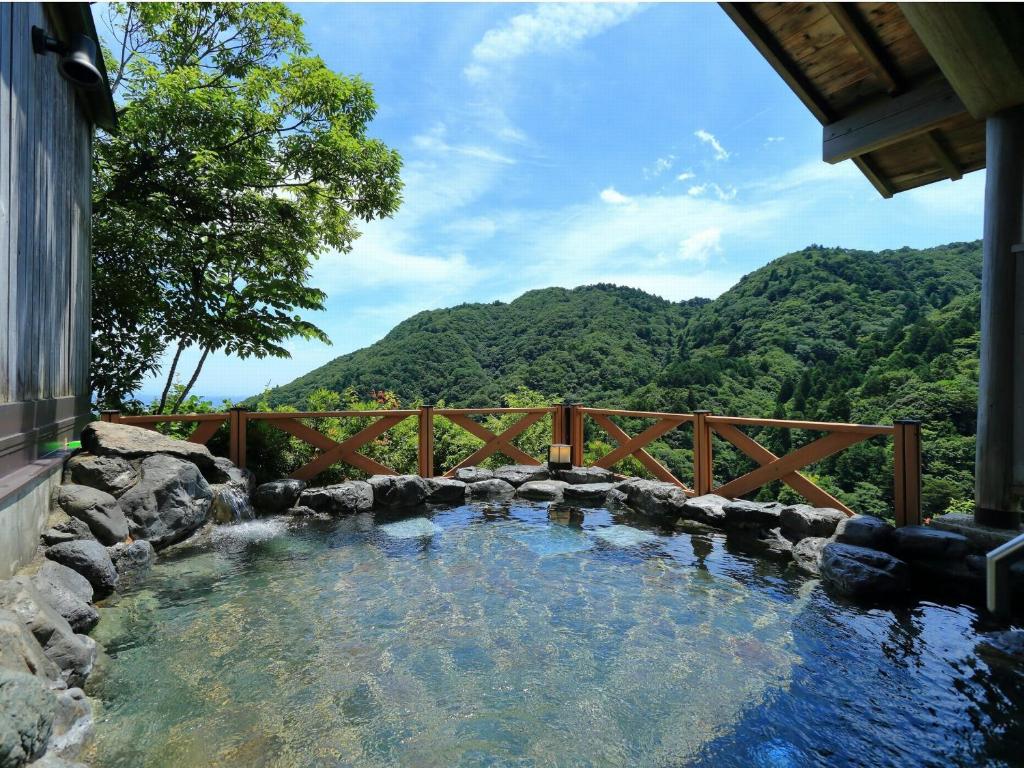 un jacuzzi dans une cour arrière avec une clôture en bois dans l'établissement Hotel Yunomoto, à Komono