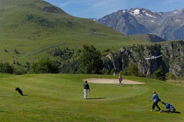 un groupe de personnes et un chien sur un parcours de golf dans l'établissement Résidence Les Mélèzes, à L'Alpe-d'Huez
