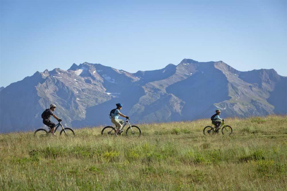 trois personnes à vélo dans un champ avec des montagnes en arrière-plan dans l'établissement Résidence Les Mélèzes, à L'Alpe-d'Huez 24 autres photos