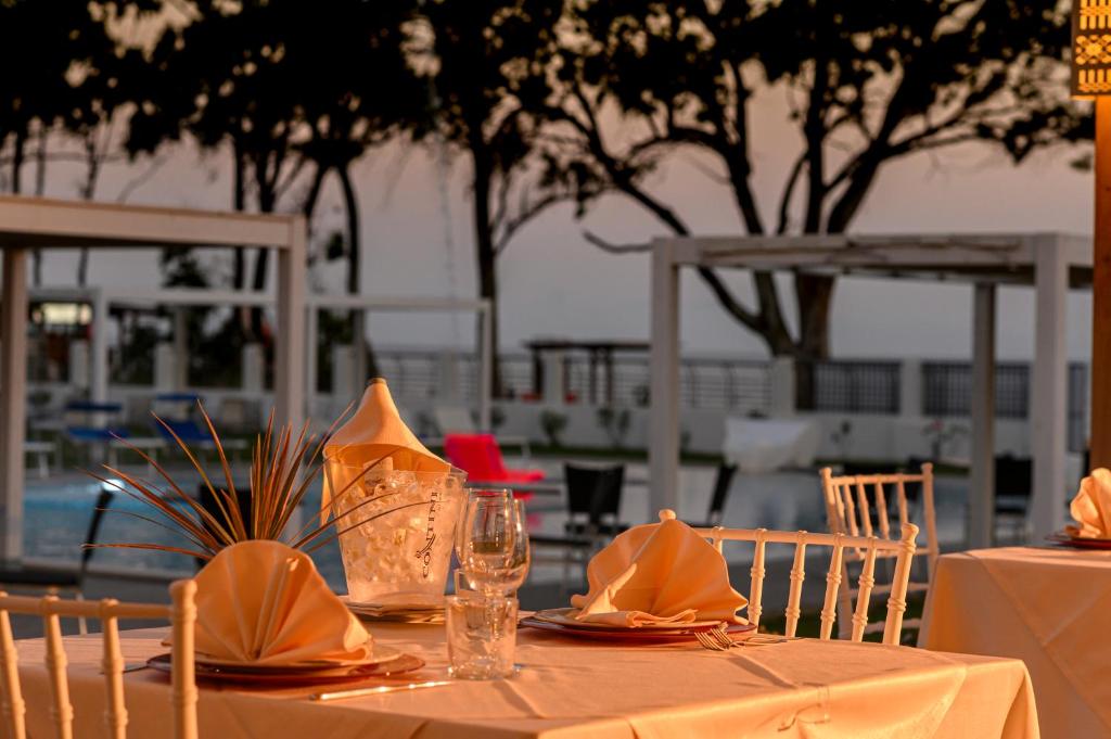 - une table avec des serviettes en orange et des verres dans l'établissement Hotel Lido Beach PHG, à Oristano