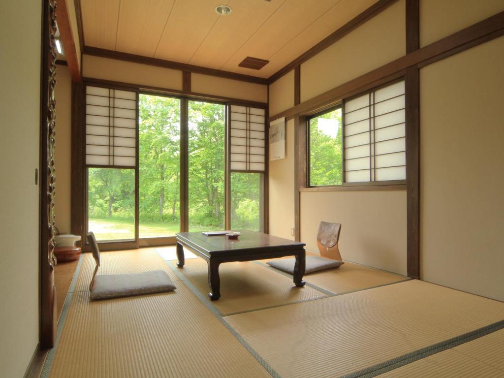 une pièce avec une table, des chaises et des fenêtres dans l'établissement Bunanoyado Koase, à Aga