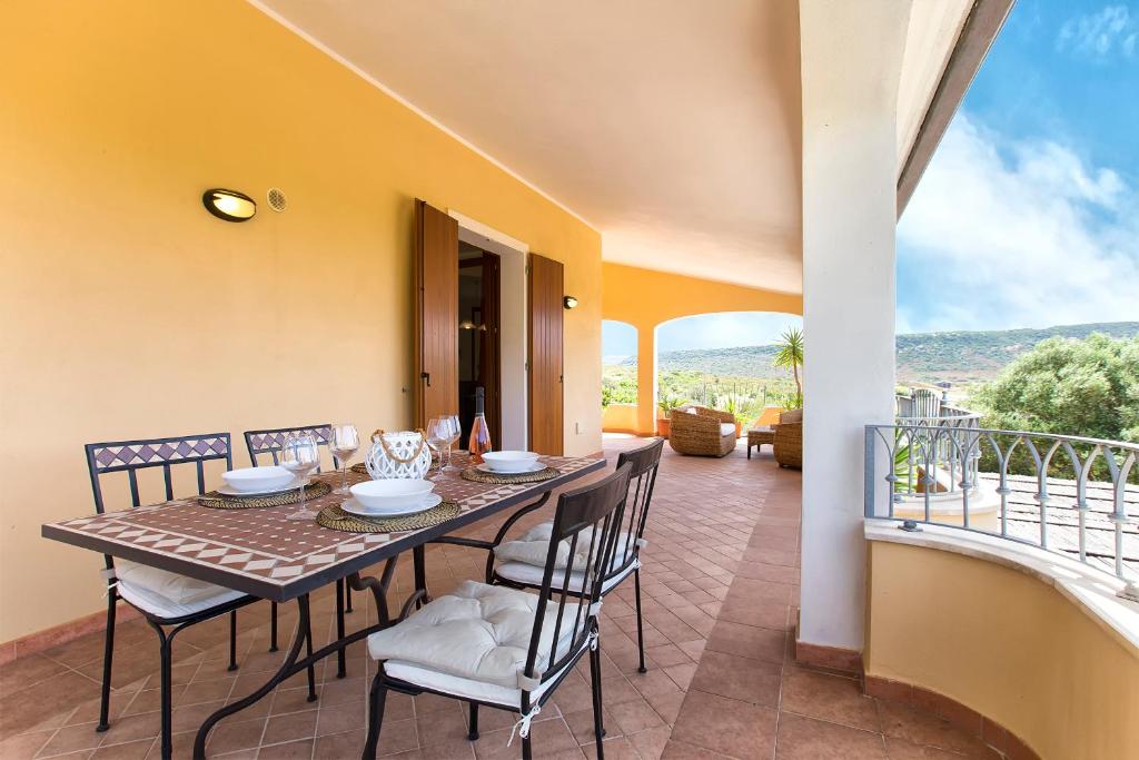 une salle à manger avec une table et des chaises sur un balcon dans l'établissement Villa Pedra Alghero - appartamento in villa con piscina, à Alghero