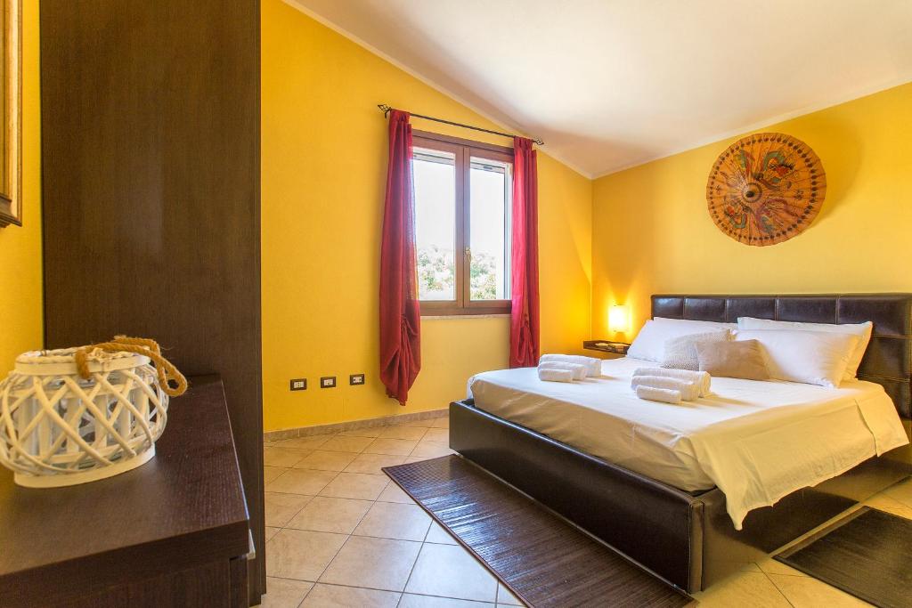 une chambre avec un lit aux murs jaunes et une fenêtre dans l'établissement Villa Pedra Alghero - appartamento in villa con piscina, à Alghero