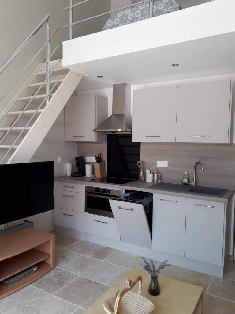 une cuisine avec des placards blancs et un escalier dans l'établissement Gîte Madeleine, à Saint-Nazaire-dʼAude 4 autres photos