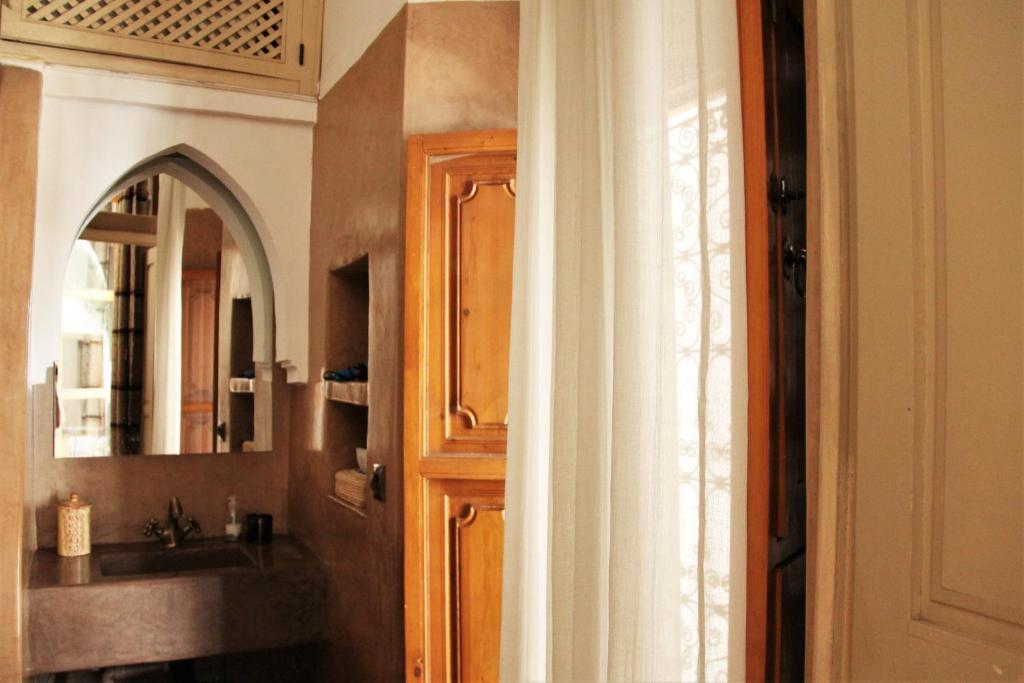 La salle de bains est pourvue d'un lavabo et d'une porte avec un miroir. dans l'établissement Riad Miski, à Marrakech