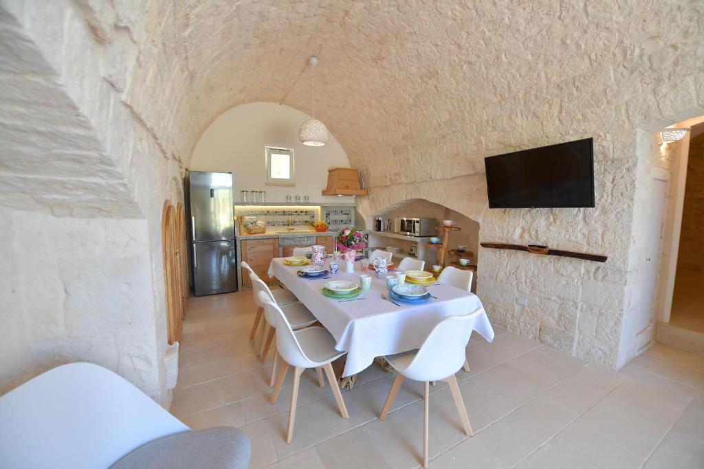 une cuisine et une salle à manger avec une table et des chaises blanches dans l'établissement Trulli Santa Croce - Luxury Holiday -, à Locorotondo