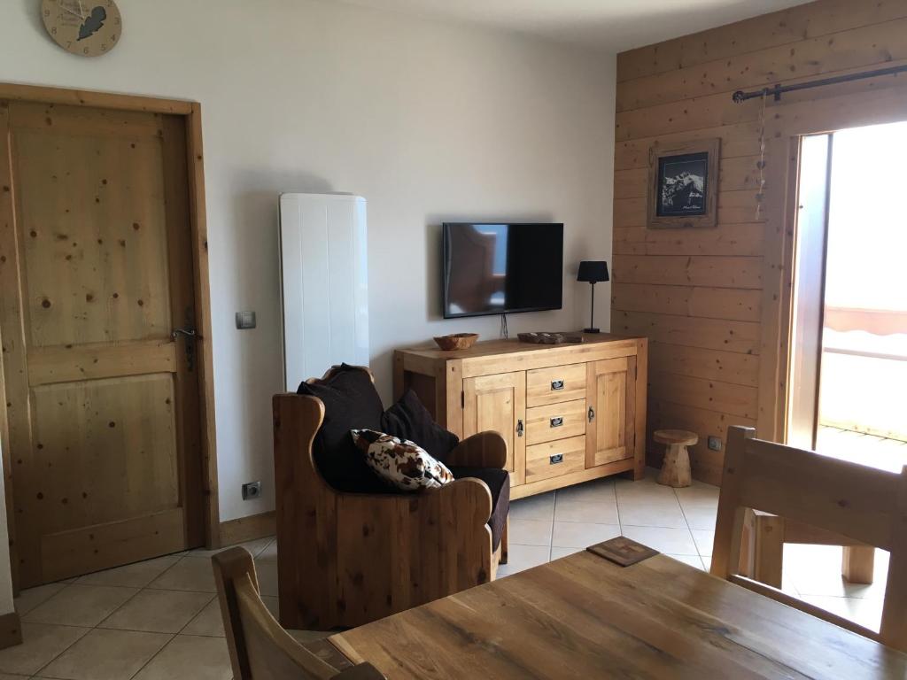 - un salon avec une télévision, une chaise et une table dans l'établissement La Perle Des Alpes C2, à Villard-sur-Doron