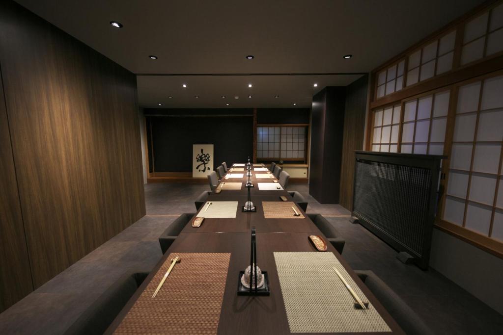 une longue rangée de tables dans une pièce avec un écran dans l'établissement Hakuunsou, à Yugawara 37 autres photos