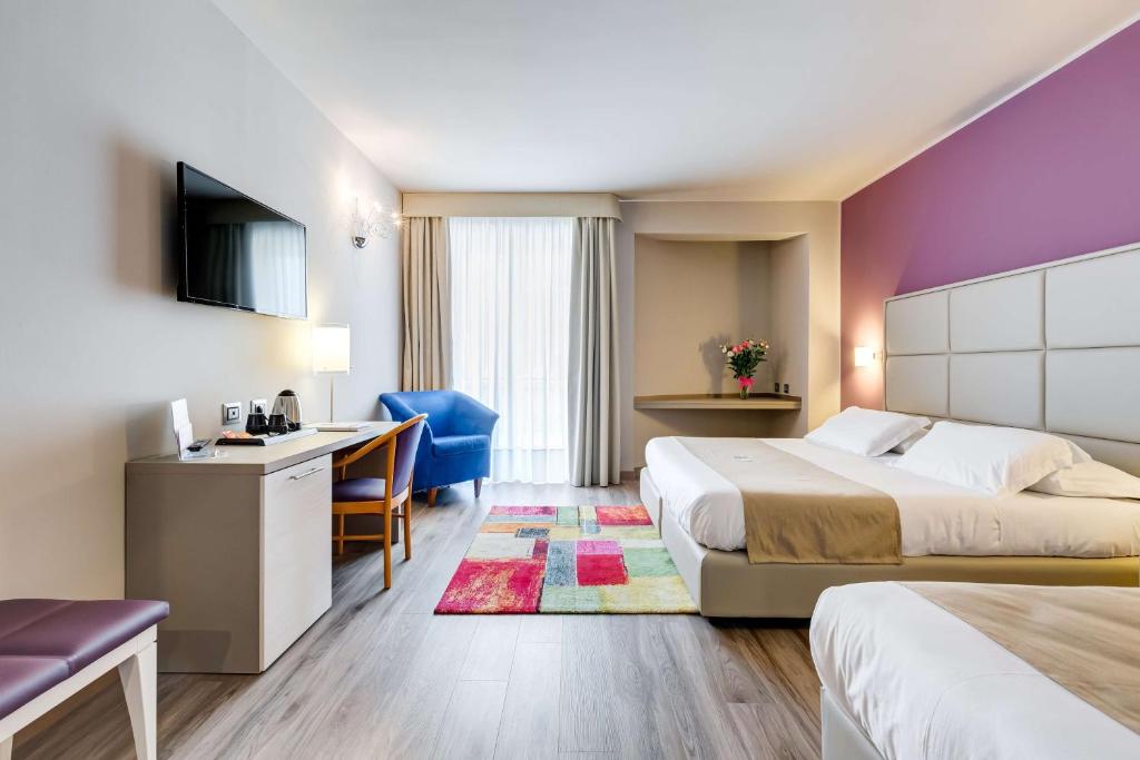 une chambre d'hôtel avec deux lits et un bureau dans l'établissement Best Western Hotel Imperiale, à Nova Siri Marina