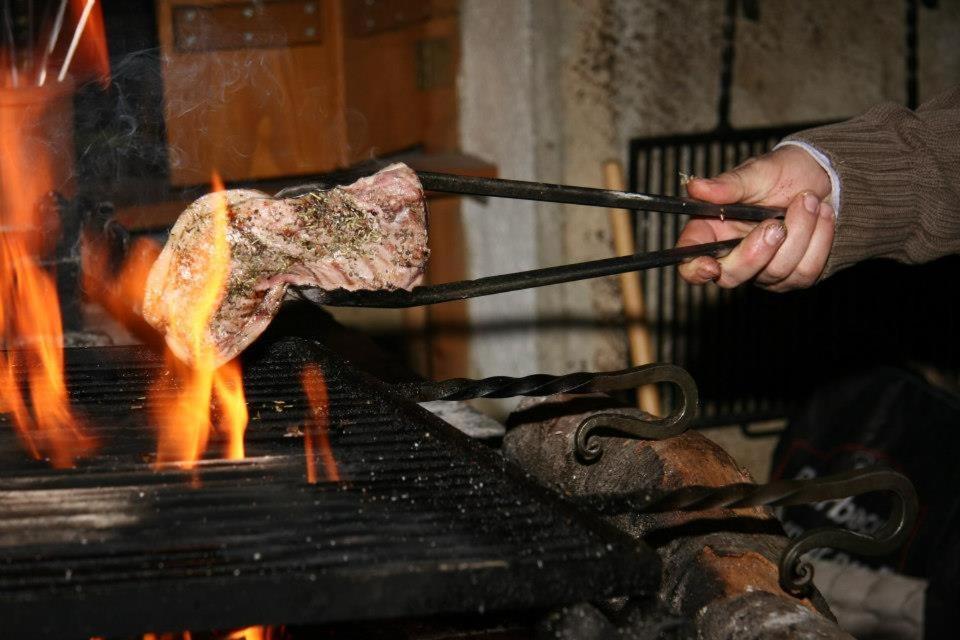 une personne qui cuisine un morceau de viande sur un grill dans l'établissement Auberge de la Perdrix, à Hauterive-la-Fresse