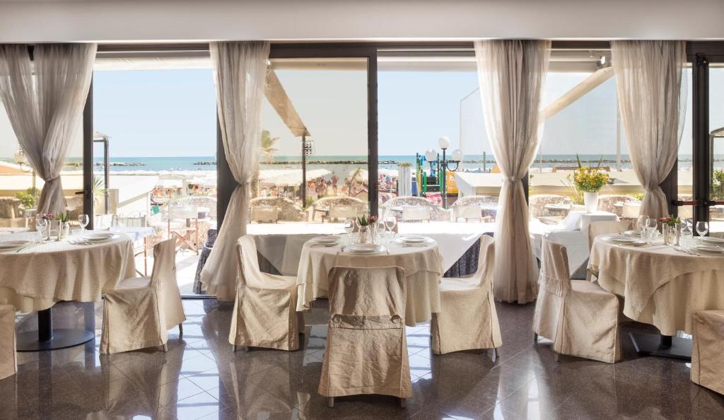 une salle à manger avec tables et chaises avec vue sur l'océan dans l'établissement Hotel Strand, à Bellaria-Igea Marina