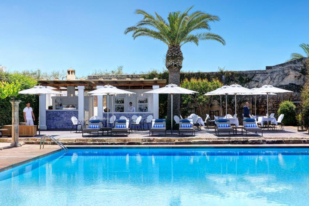 une piscine avec chaises et parasols dans l'établissement Rocco Forte Masseria Torre Maizza, à Savelletri di Fasano