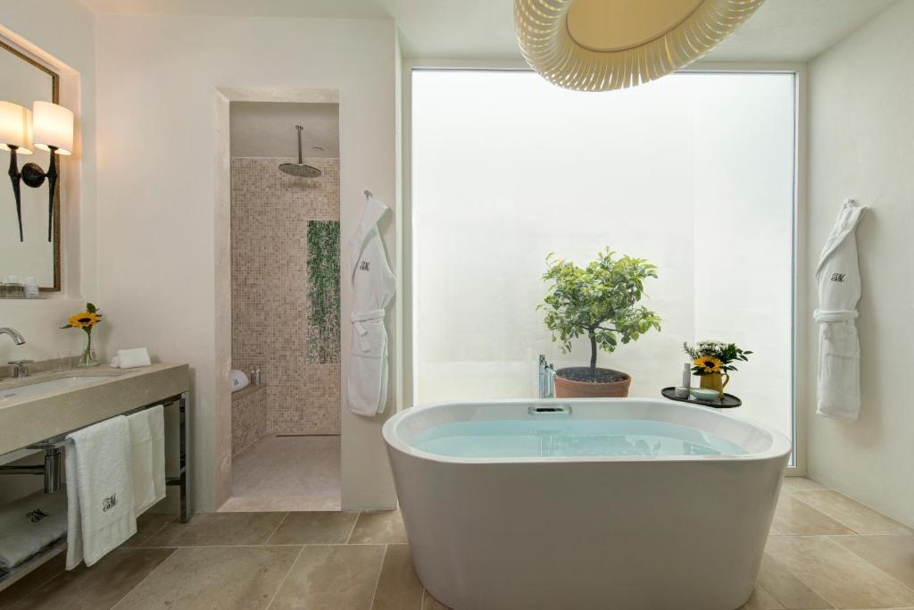 une grande salle de bain avec baignoire et douche dans l'établissement Rocco Forte Masseria Torre Maizza, à Savelletri di Fasano