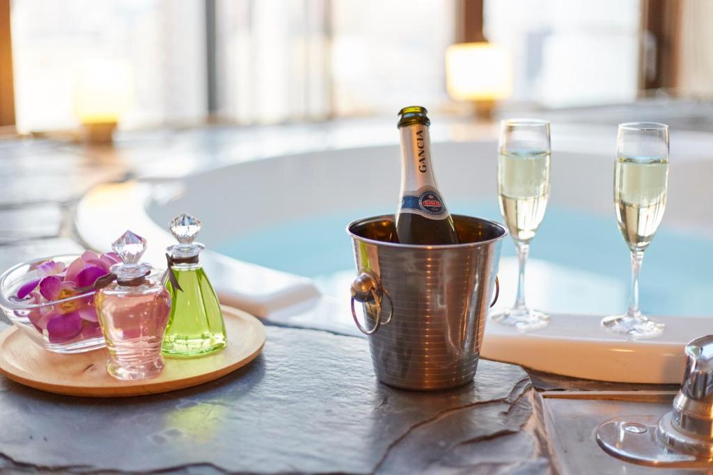 - une bouteille de champagne dans un seau sur une table avec des verres dans l'établissement ホテル ジュエリージュエリー 十三, à Osaka