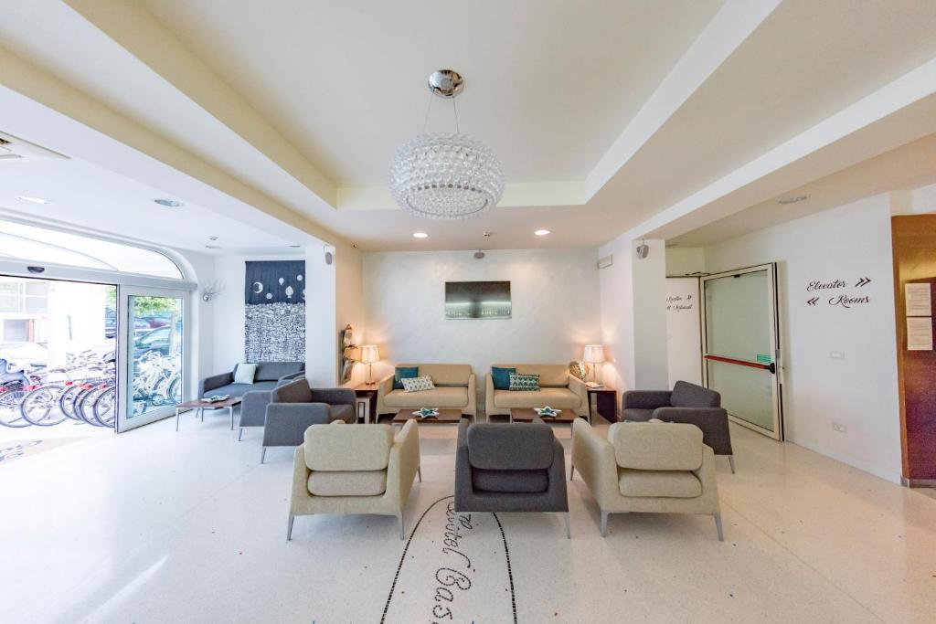 - un salon avec des canapés et des chaises dans l'établissement Hotel Castiglione, à Lignano Sabbiadoro